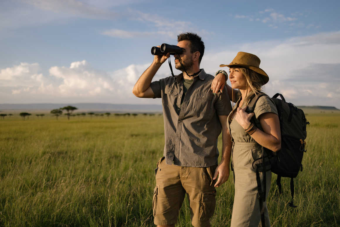 A couple using binoculars to spot wildlife in safari