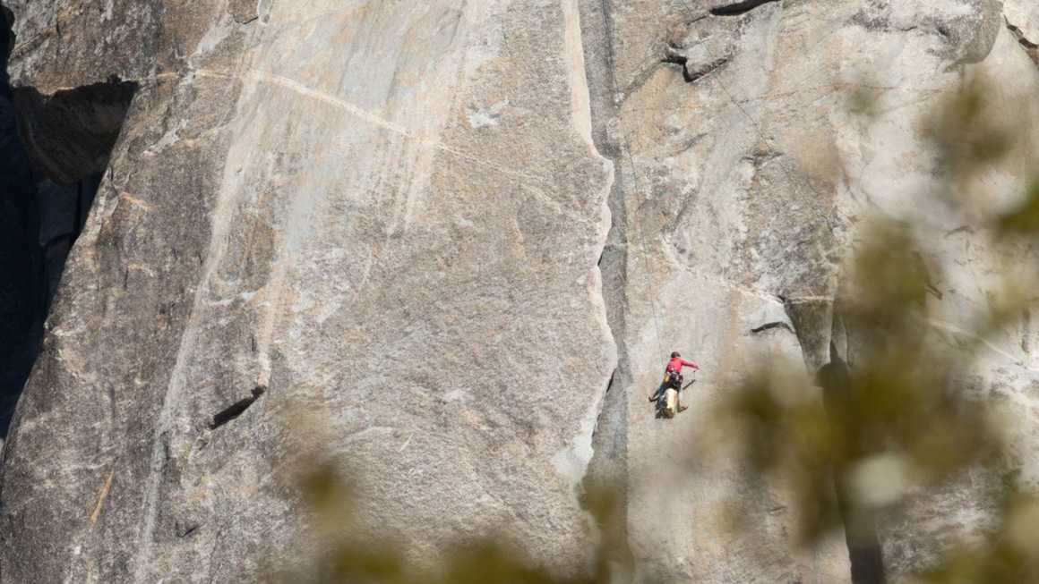 a rock climber making their way up a big wall in yosemite
