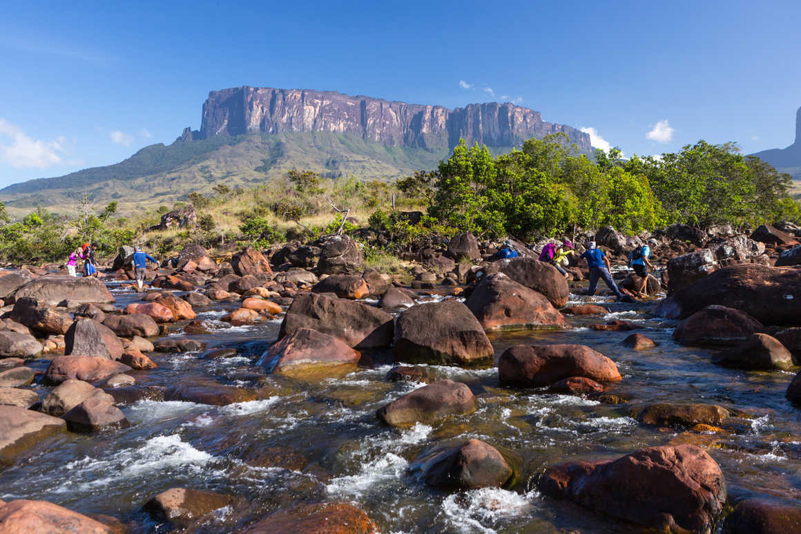 A tepui in Guyana with a river and a group crossing it