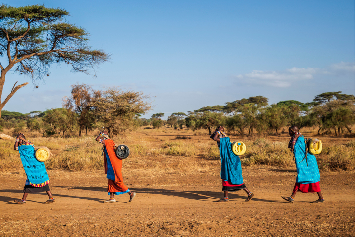 African women from Maasai tribe carrying water to their village, Kenya, Africa.