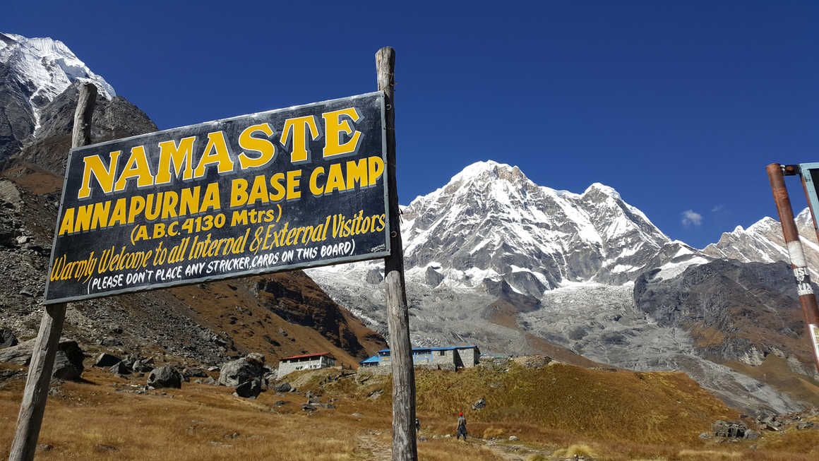 Annapurna Base Camp sign with mountain ranges in the distance, Nepal