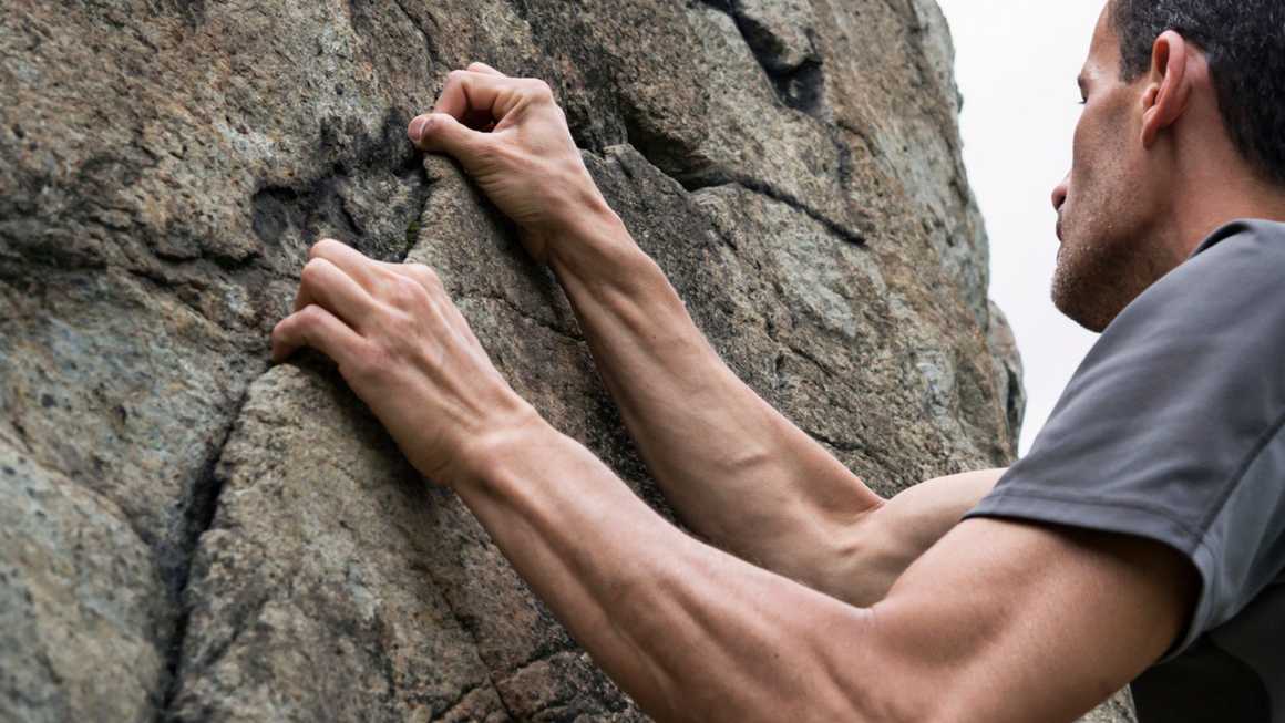 Climber pulling on small ledge while climbing
