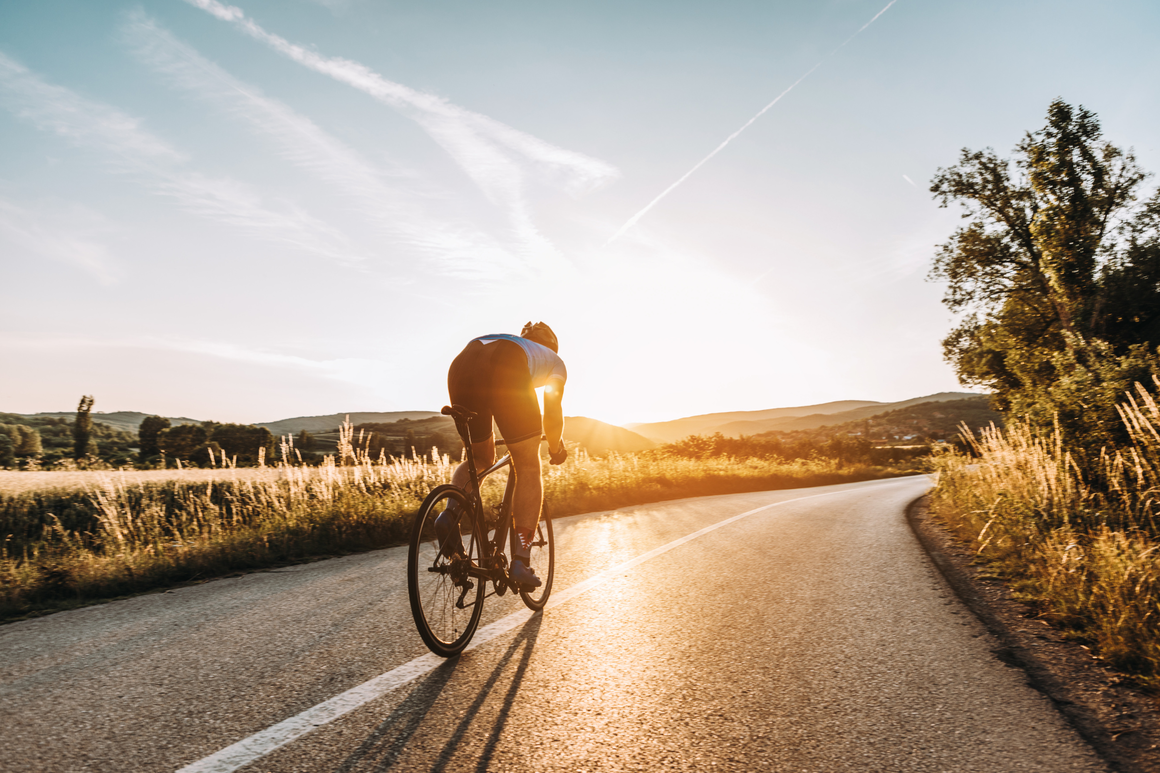 Cyclist cycling along a road at sunset