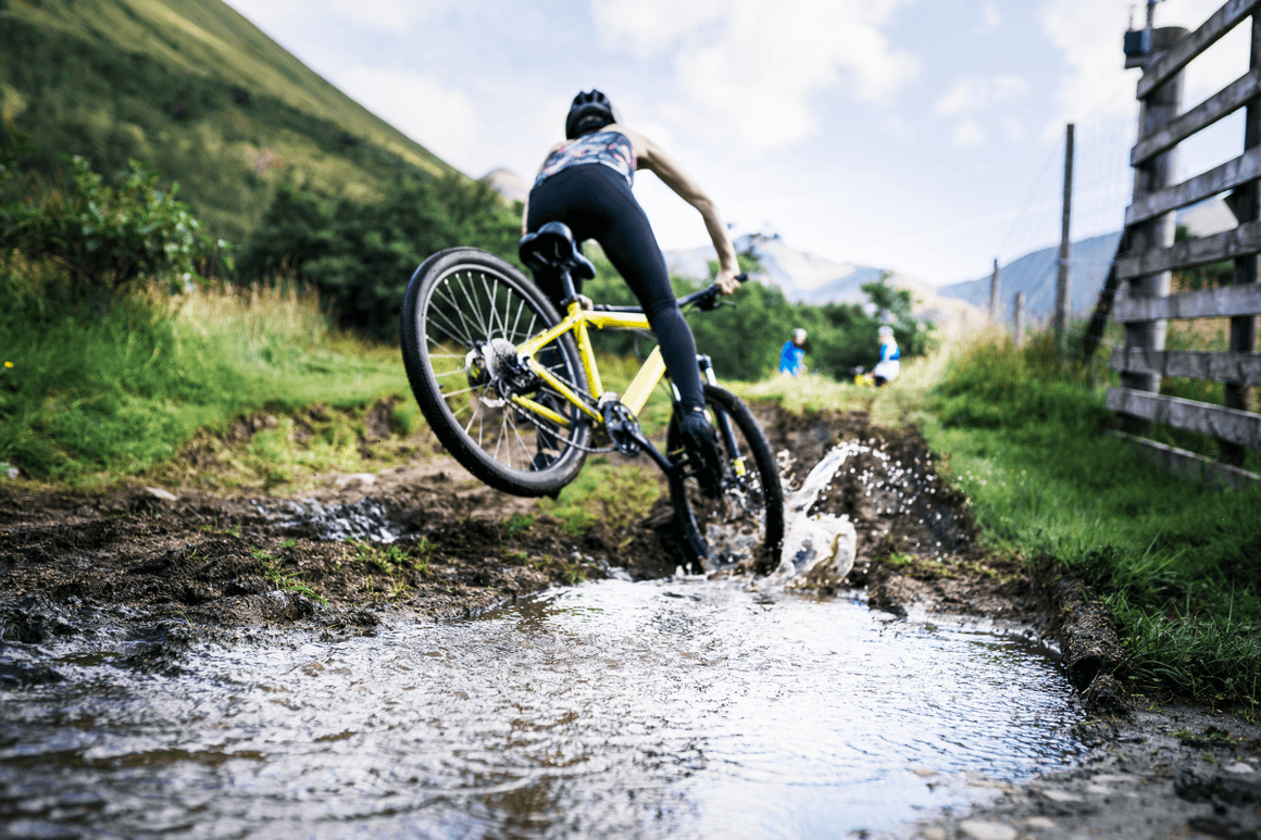 Female mountain biker cycling through natural british landscape