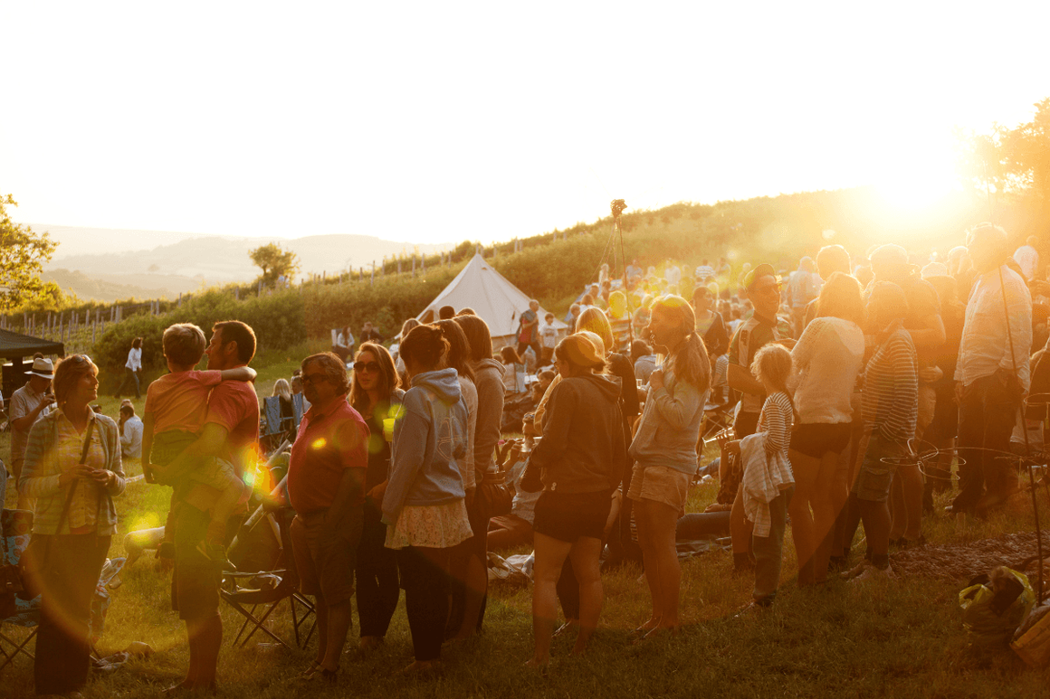 Group of festival goers socialising  in sunny field