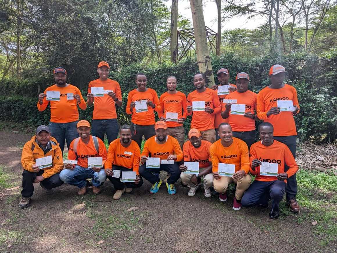 Group of Kandoo guides in orange t-shirts holding their safety training certificates