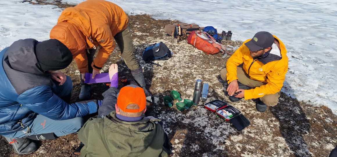 Guide bandaging a sprained ankle on a rock amongst the ice