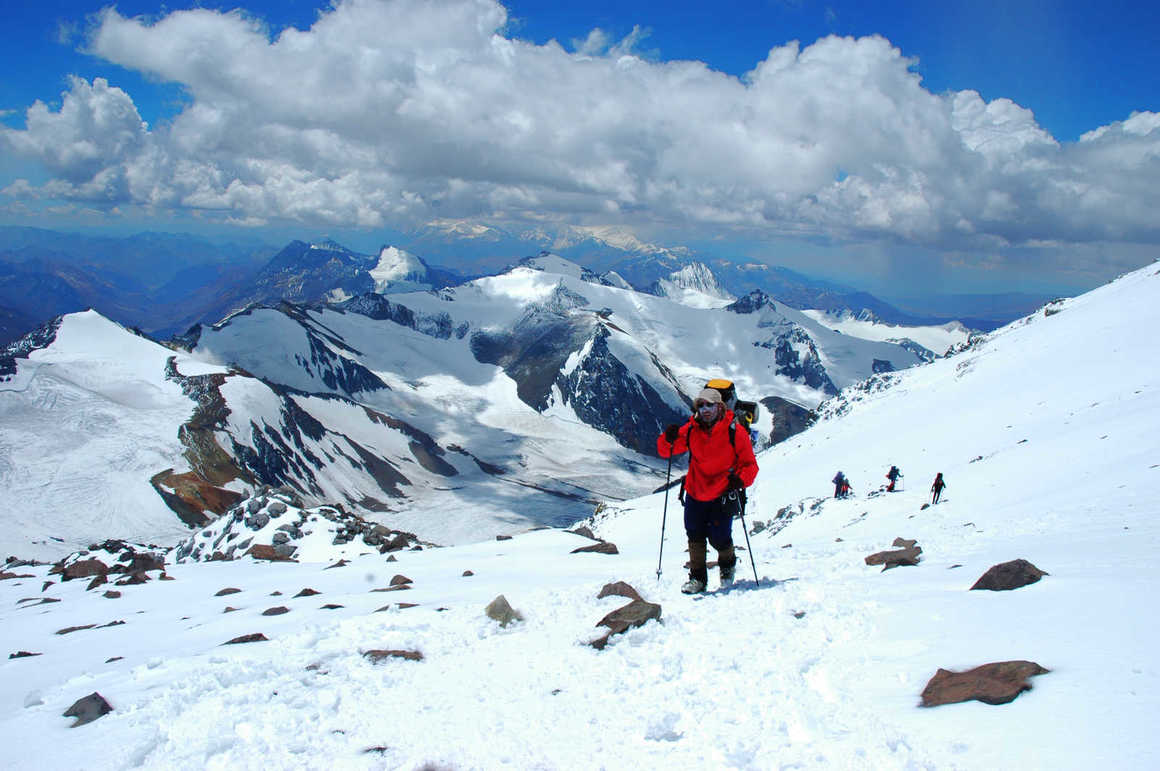 hiker climbing  Aconcagua surrounded by snow covered mountains