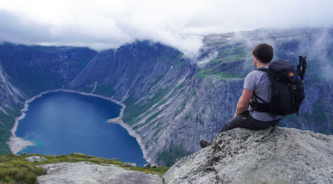Hiker takes a break looking over a lake on the Trolltunga hike in South Norway
