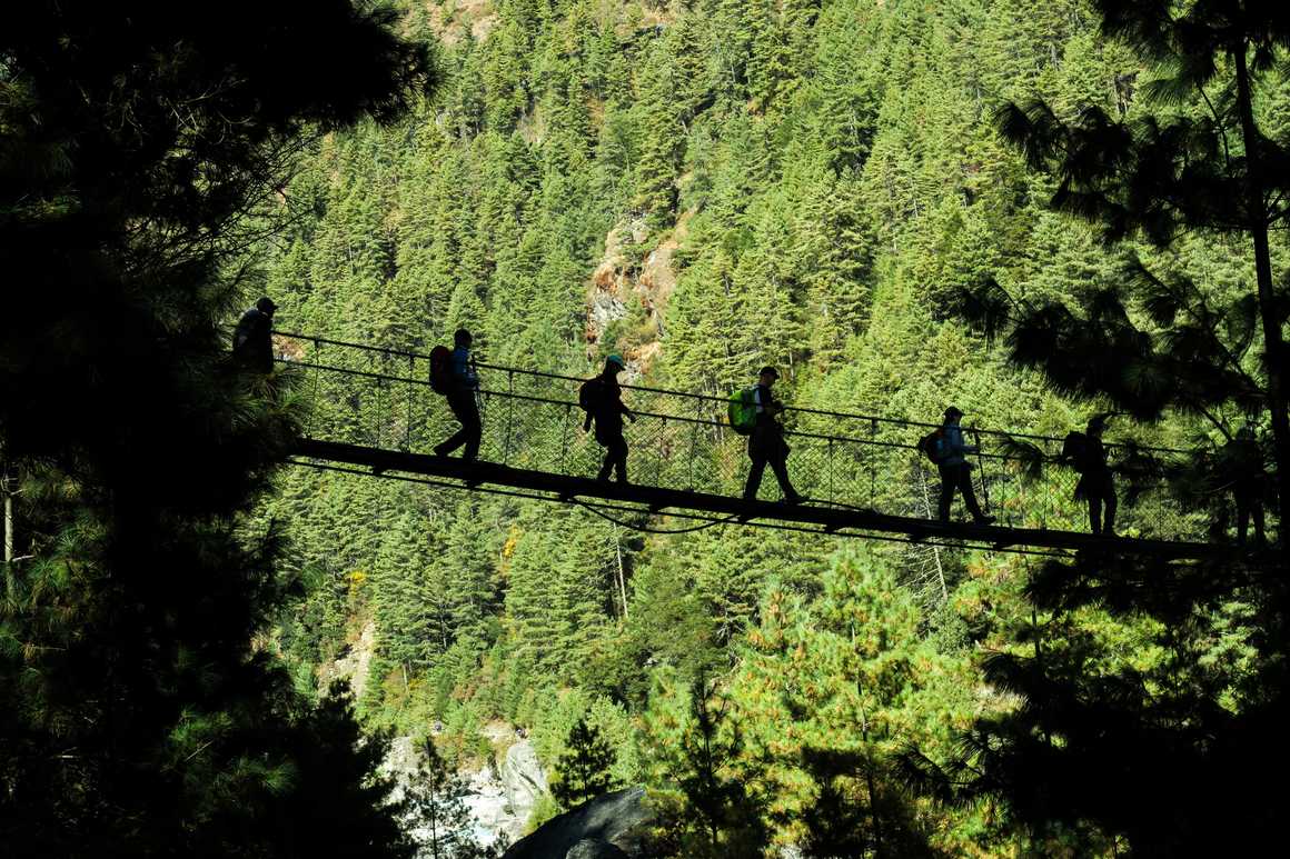 Hikers walking on suspended bridge in Padking, Nepal