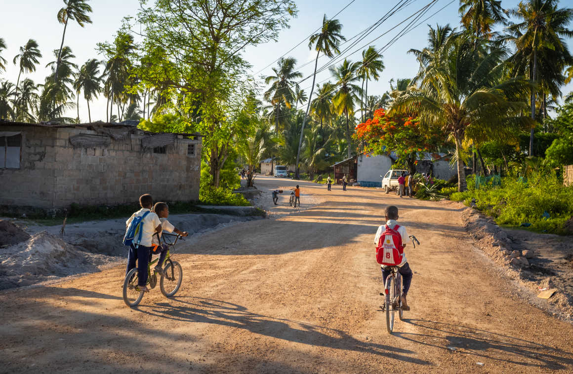 Kids riding their bikes along muram roads in Tanzania