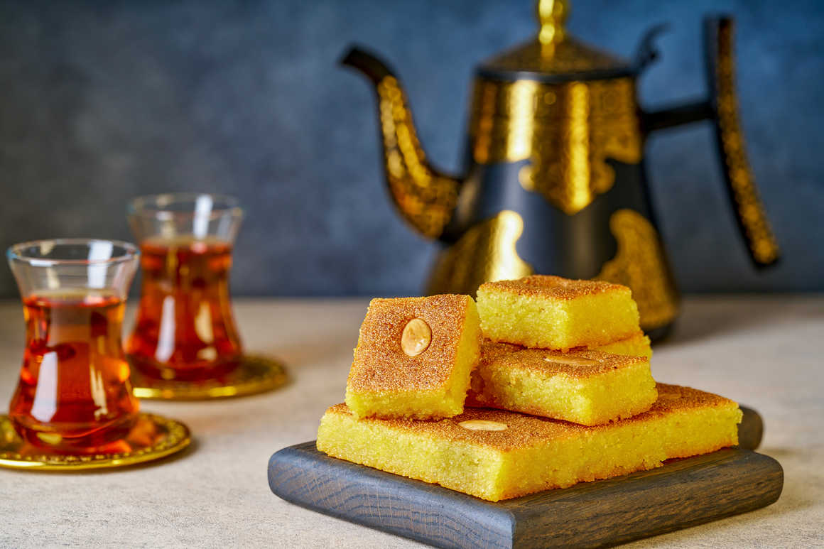 Moist Arabic almond semolina cake with mint tea in glasses and ornate teapot