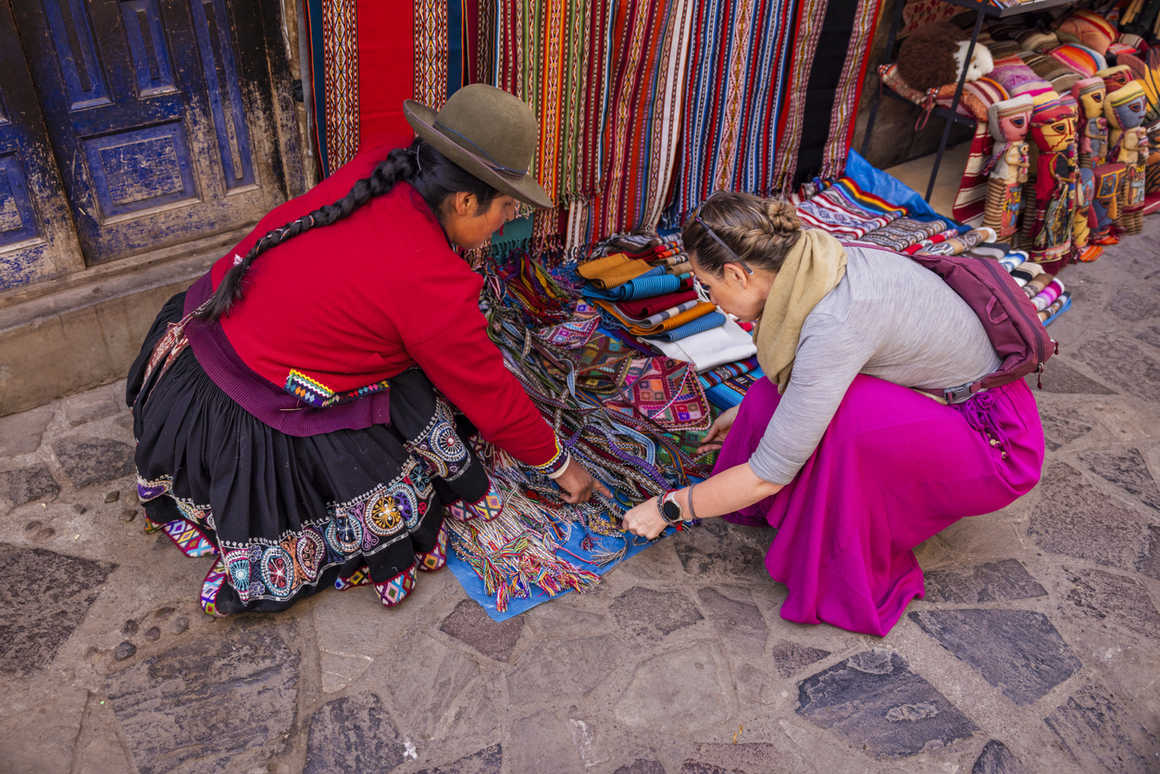 Peruvian woman weaving and selling souvenirs in Pisac market