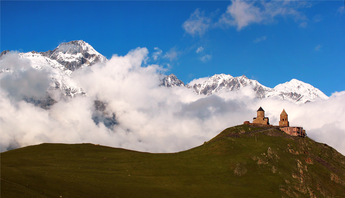 The gergeti trinity church purched on a hill above the clouds
