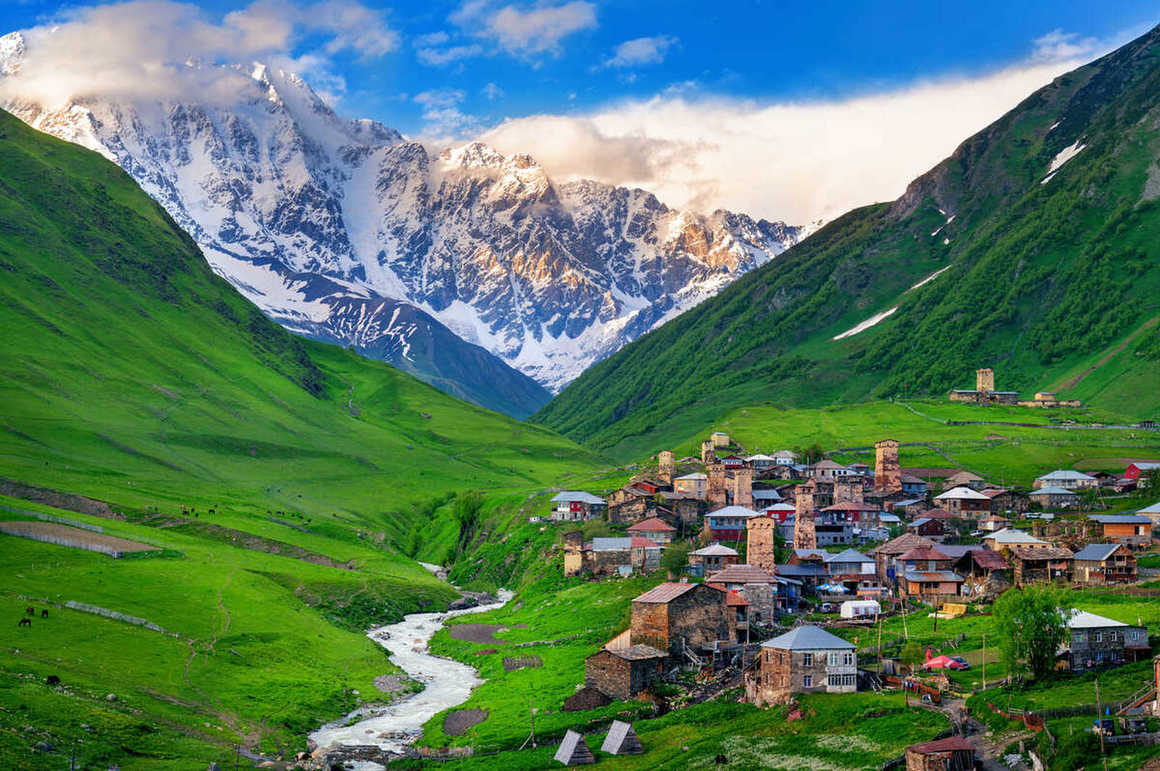 The small town of ushguli nestled amung green hills and snowy mountains