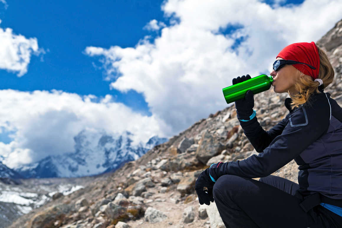 woman having a drink while trekking in Nepal