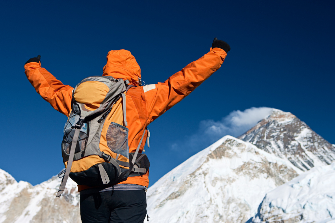 Woman lifts her arms in victory, climbing Mount Everest