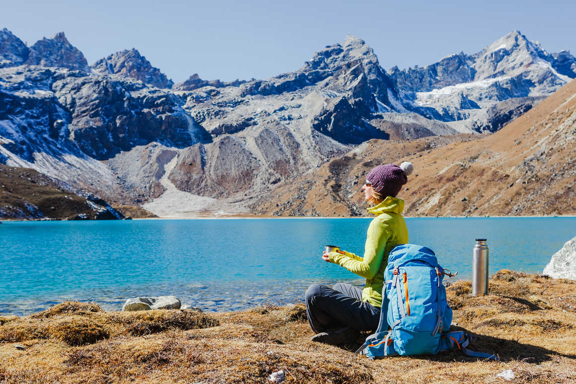 Woman on lake edge drinking amidst the Himalaya