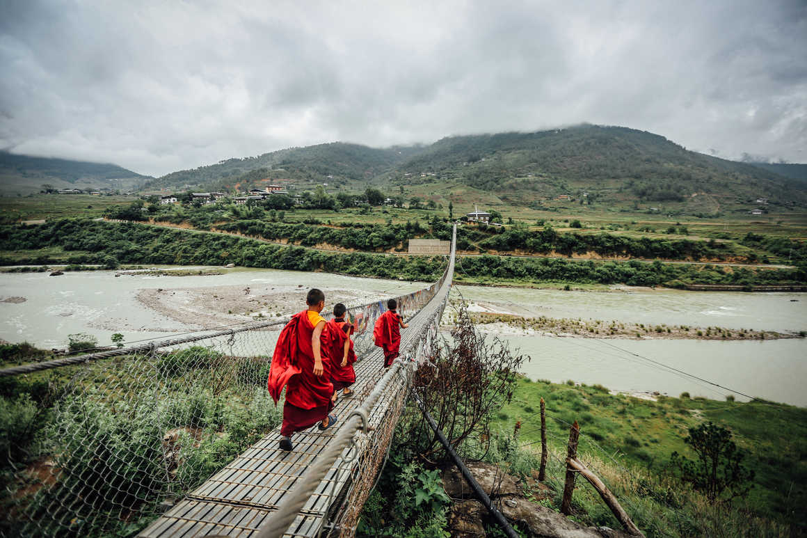 Young monks walking on a rope bridge in Bhutan