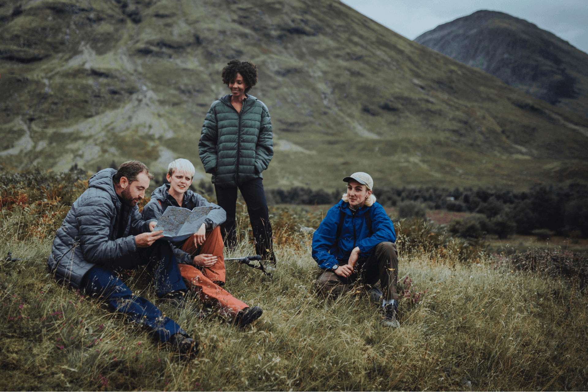 Four trekkers navigating and resting in british mountains/hills