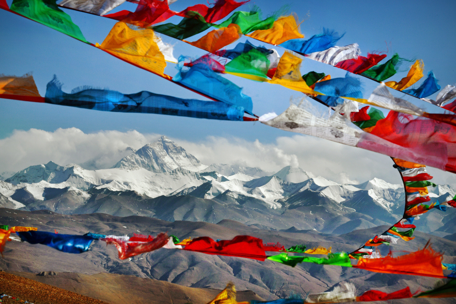Mount Everest in Himalayas of Tibet viewed at distance through Buddhist prayer flags strewn across a high Himalayan Mountain pass