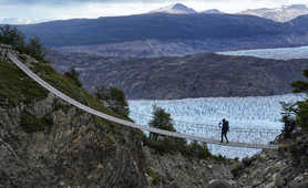 Hiker walking on a bridge over a glacier