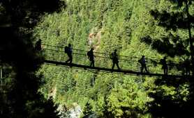 Hikers walking on suspended bridge in Padking, Nepal