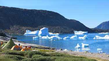 Camp on the coast of Greenland in front of icebergs