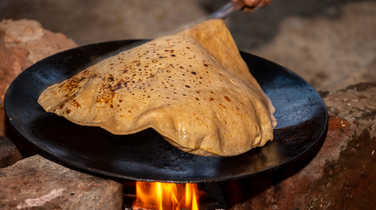 Cooking roti on a traditional clay oven