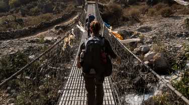 Hikers crossing a bridge during the Manaslu Circuit Trek