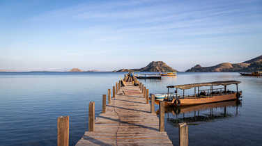 Small boats moored to a small jetty in Komodo Nature Reserve at sunrise