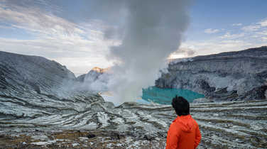 Traveller looking at crater blue lake at Kawah Ijen, Indonesia