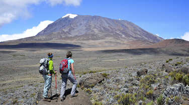 Two hikers looking at the Mount Kilimanjaro