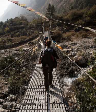 Hikers crossing a bridge during the Manaslu Circuit Trek