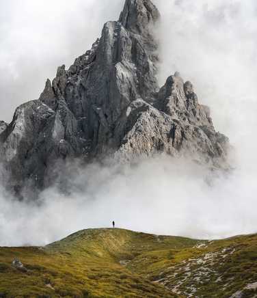 Trekker standing in front of steep mountain in the Dolomites