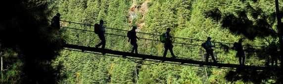 Hikers walking on suspended bridge in Padking, Nepal