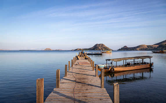 Small boats moored to a small jetty in Komodo Nature Reserve at sunrise
