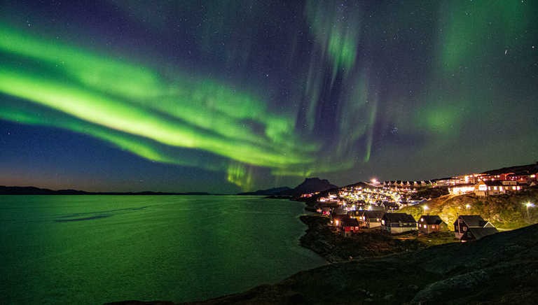 northern-lights-dance-over-a-Greenlandic-settlement